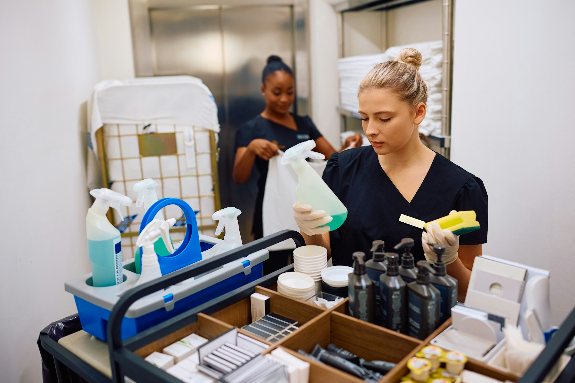 Young maid restocking a cart before cleaning a hotel guest room.